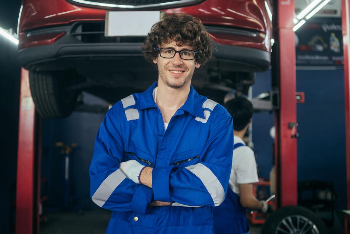 Car mechanic standing with arms crossed looking at car for lockout service